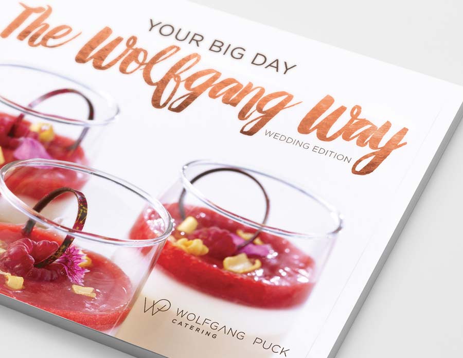 Close-up of a Wolfgang Puck catering wedding booklet, created by the Braintrust team, featuring raspberry desserts on the cover.