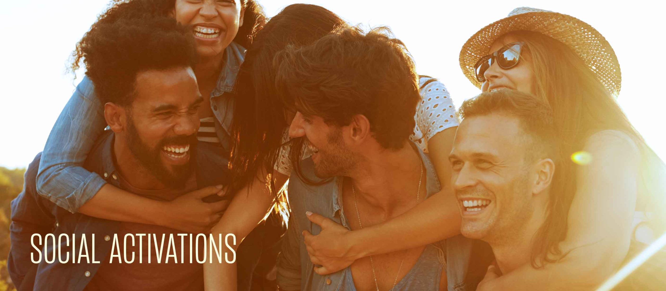 A group of friends laughing and smiling outdoors in sunlight, with SOCIAL ACTIVATIONS text in the corner.