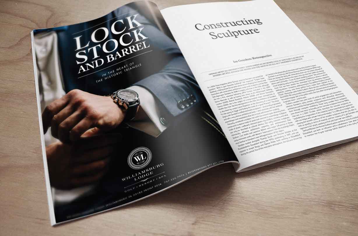 Open magazine on a table, showing an article and an ad featuring a man in a suit adjusting his watch.