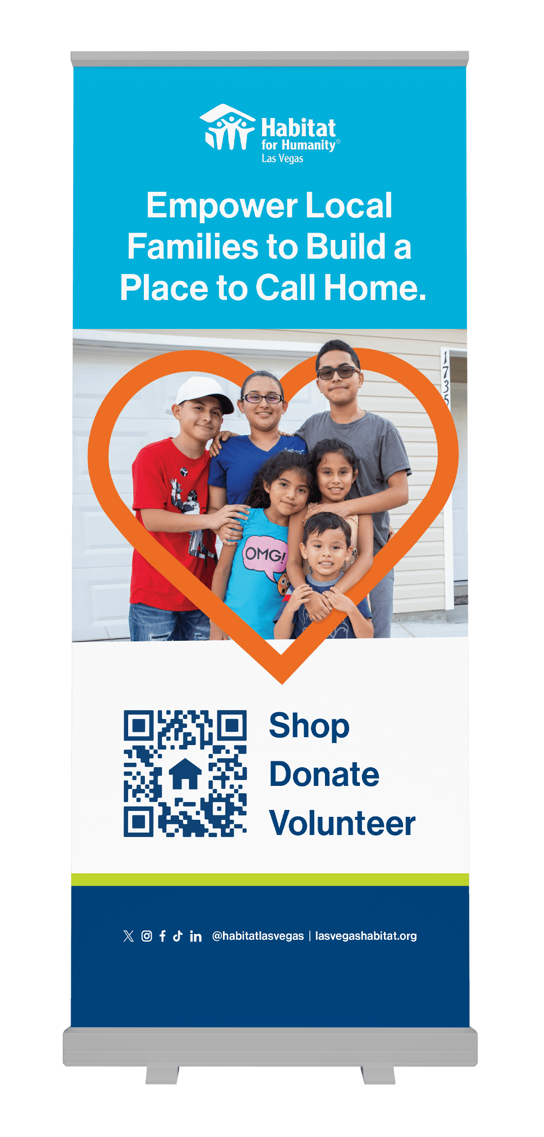 A family of five smiles inside a heart frame on a Habitat for Humanity Las Vegas volunteer banner.
